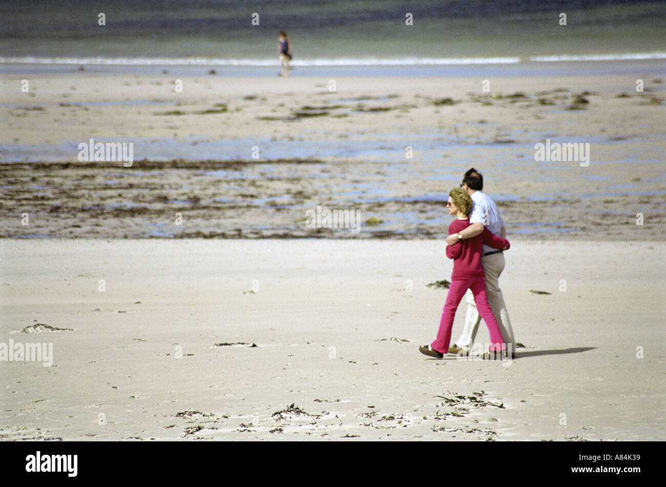 Coppia di mezza età passeggiare su una vasta spiaggia di sabbia Foto Stock