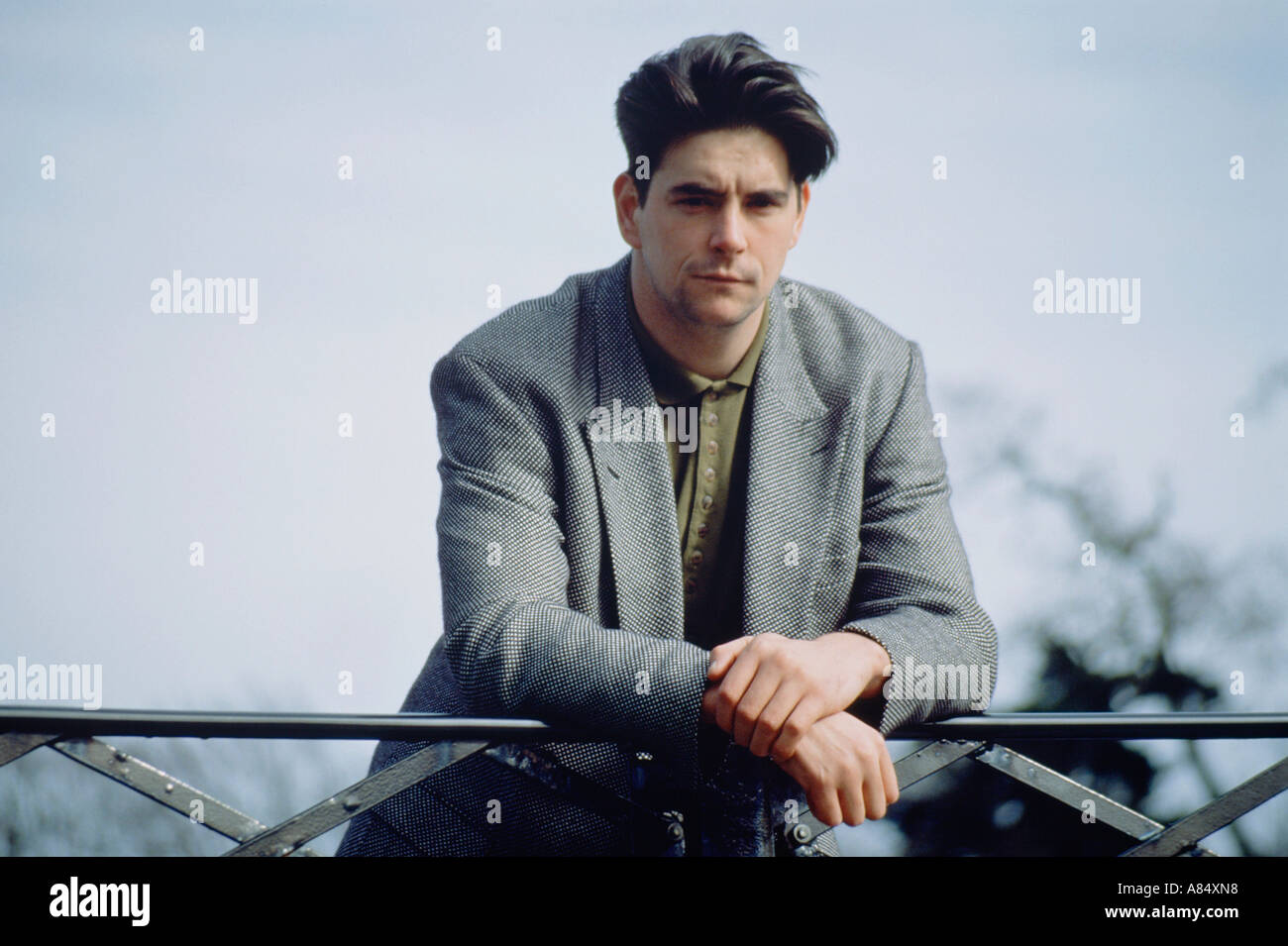 Outdoor Ritratto di giovane uomo in piedi sul ponte del parco. Foto Stock