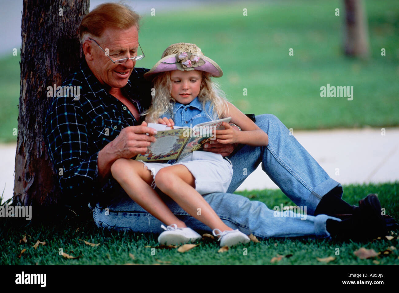 Nonno e nipote seduto sull'erba nel parco della città. Queensland. Australia Foto Stock