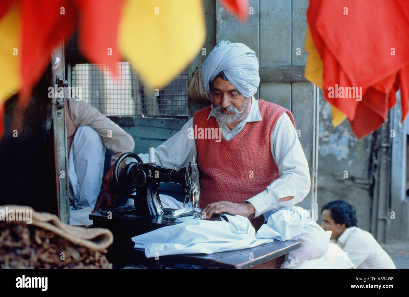 India. Delhi. Industria locale. La religione sikh uomo lavorando su misura della macchina per cucire. Foto Stock