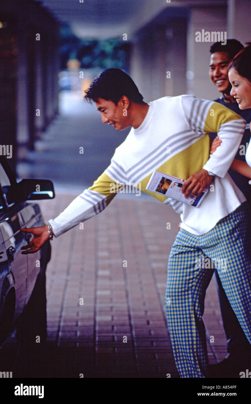 Singapore. Coppia giovane in taxi. Uomo di raggiungere per maniglia per porte di veicoli. Foto Stock