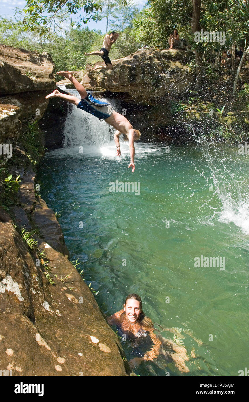 Un gruppo di turisti europei in Brasile rinfrescarvi presso il campeggio diving e saltando da una corda swing in una piscina di acqua fresca. Foto Stock