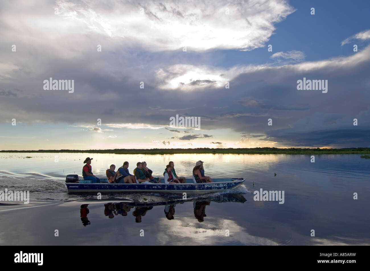 Un gruppo di turisti europei godendo di una gita in barca sul pantanal in Brasile al tramonto. Foto Stock