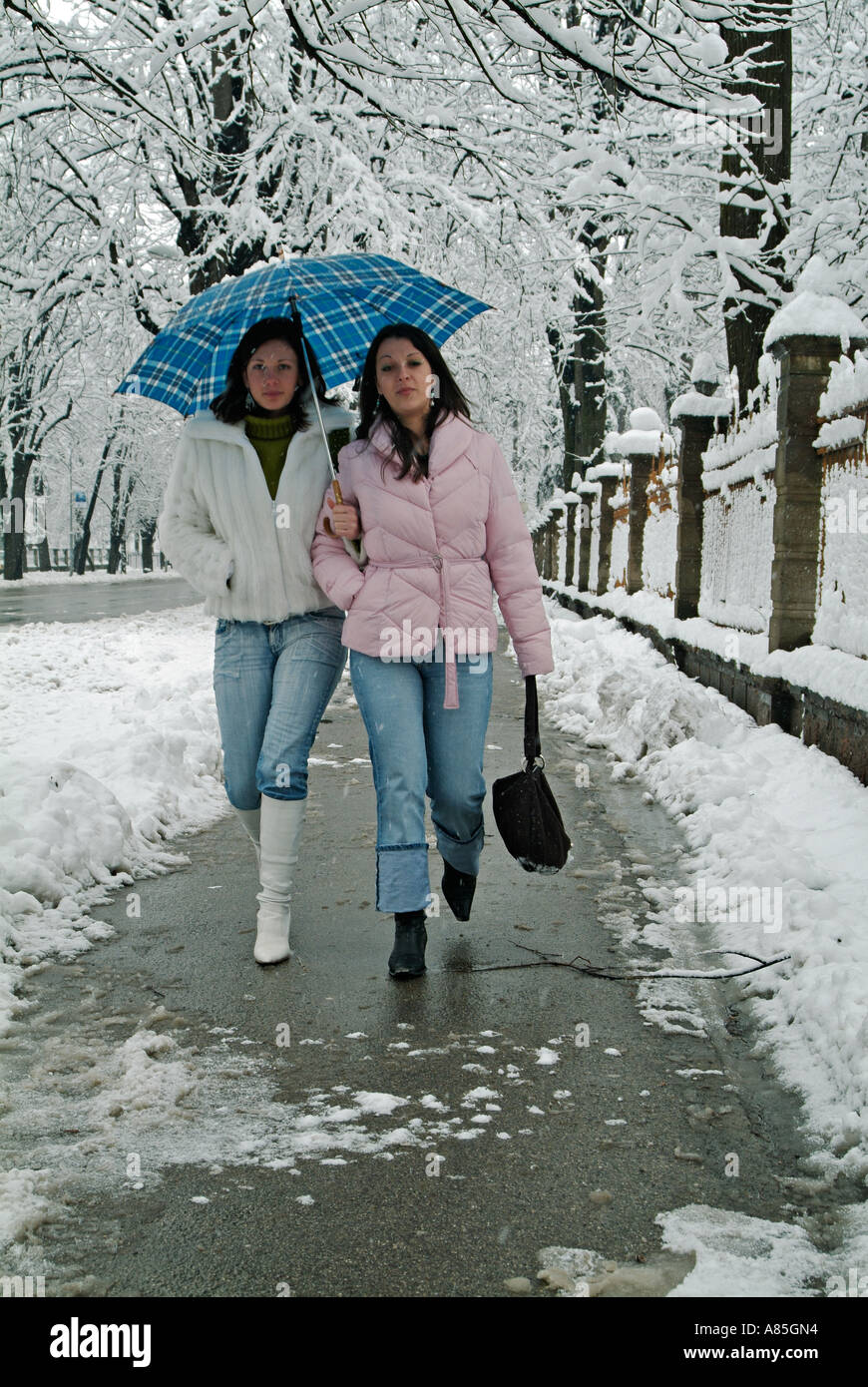 Due giovani caucasici donna camminando lungo una città europea marciapiede durante l'inverno la neve Foto Stock