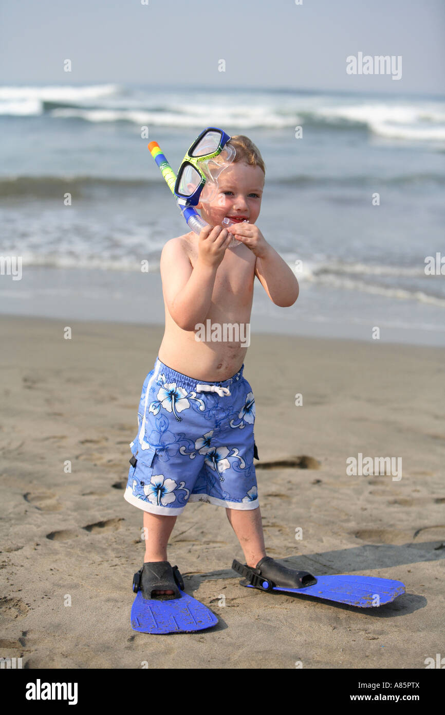 Bimbo di 2 anni con equipaggiamento da snorkel e pinne presso la spiaggia Foto Stock