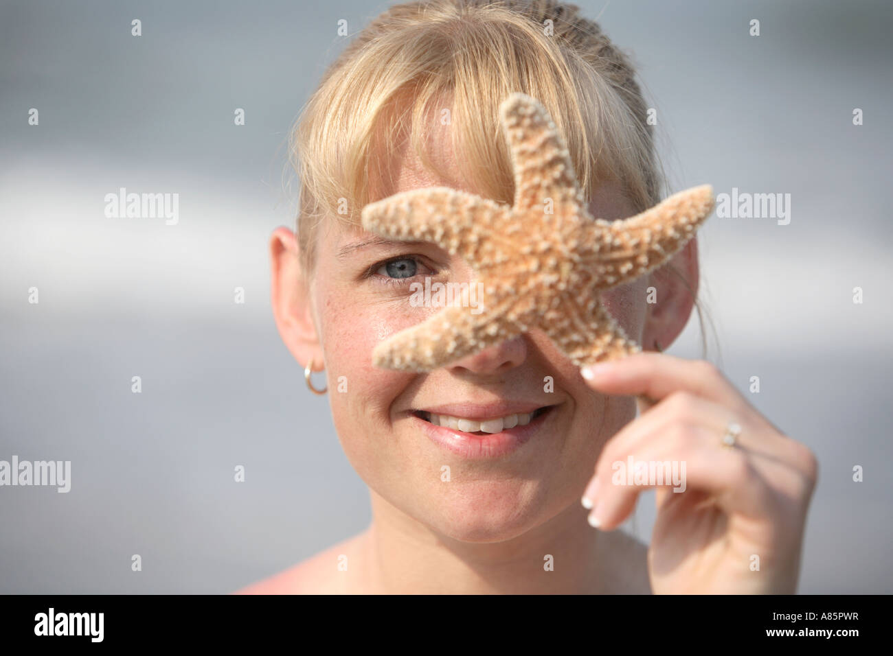 Donna con stella di mare oltre il suo volto Foto Stock