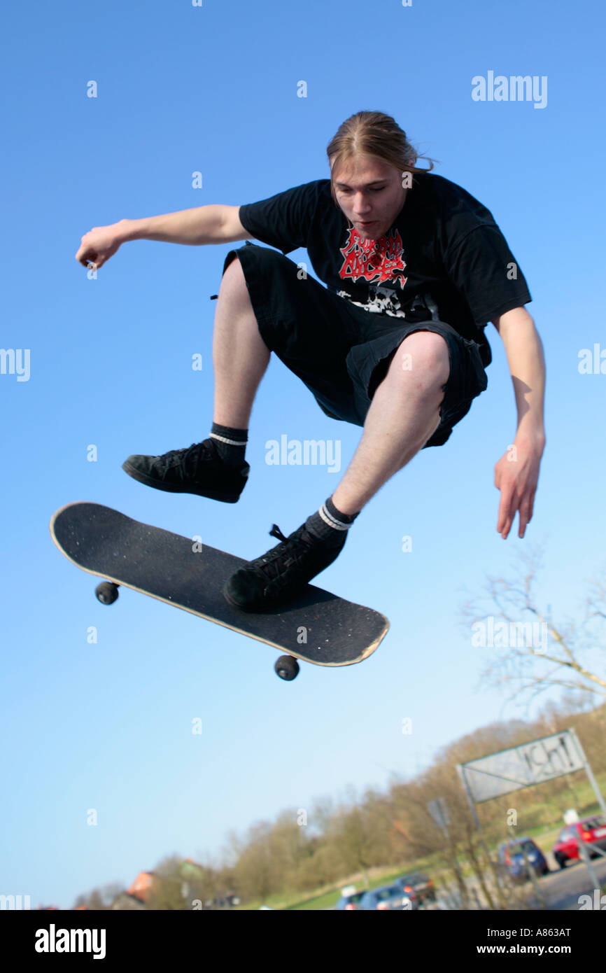 Un giovane pattinatore salta con il suo skateboard Foto Stock