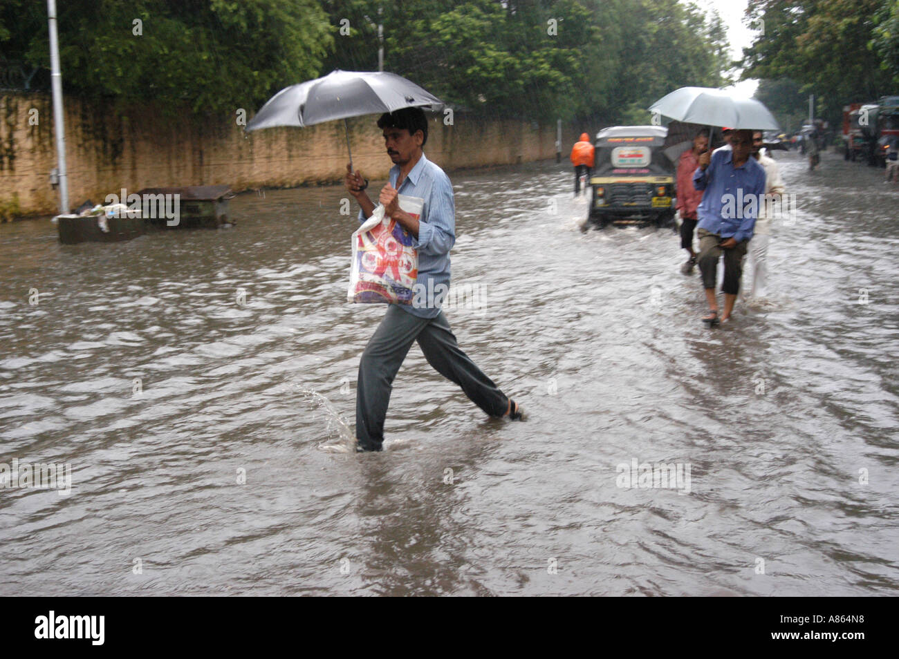 Popolo Indiano a piedi attraverso strade allagate dalle piogge monsoniche a Bombay Mumbai India Foto Stock