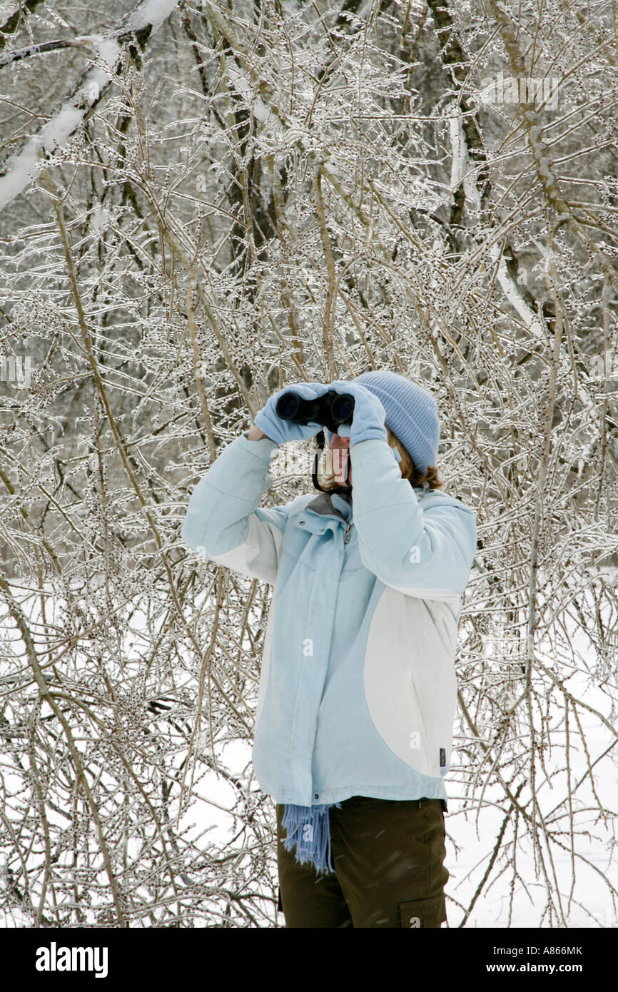 Femmina invernale di osservazione degli uccelli con il binocolo in tempesta di ghiaccio - Verticale Foto Stock