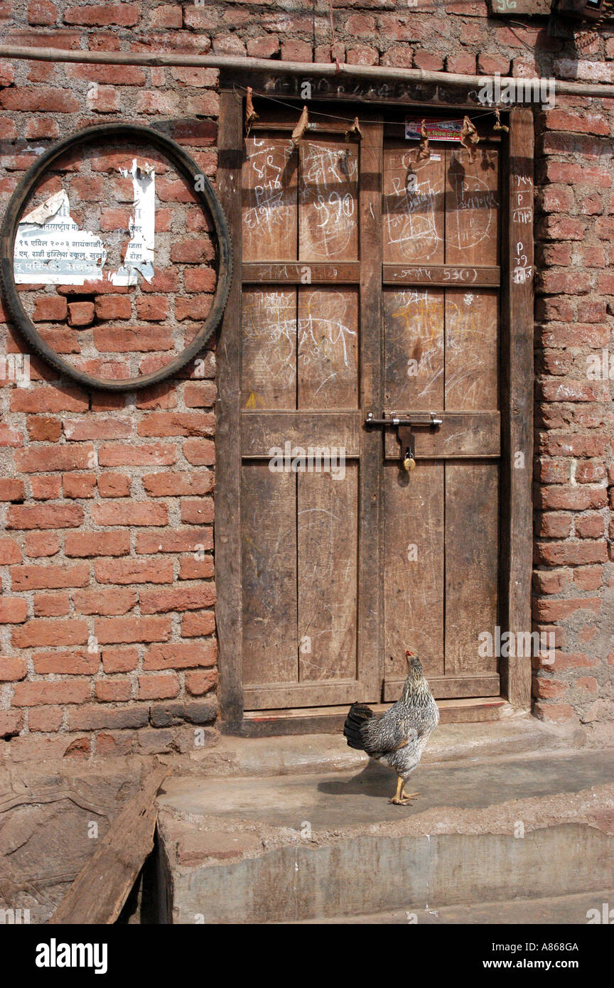 MPD77542 chiuso lo sportello ligneo sul muro di mattoni con ciclo pneumatico e gallina Roha nella piccola città nel distretto di Raigad del Maharashtra India Foto Stock