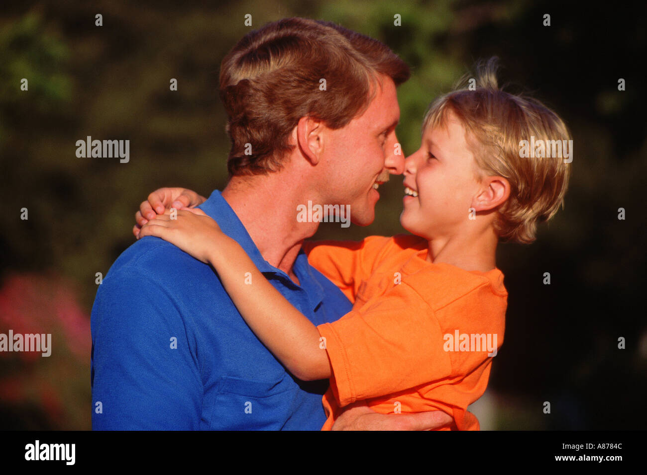 Giovane persone sorridenti papà tenendo poco 5-7 anno vecchio ragazzo nelle sue braccia il naso a naso all'aperto in una giornata di sole Caucasian signor © Myrleen Pearson .......Ferguson Cate Foto Stock