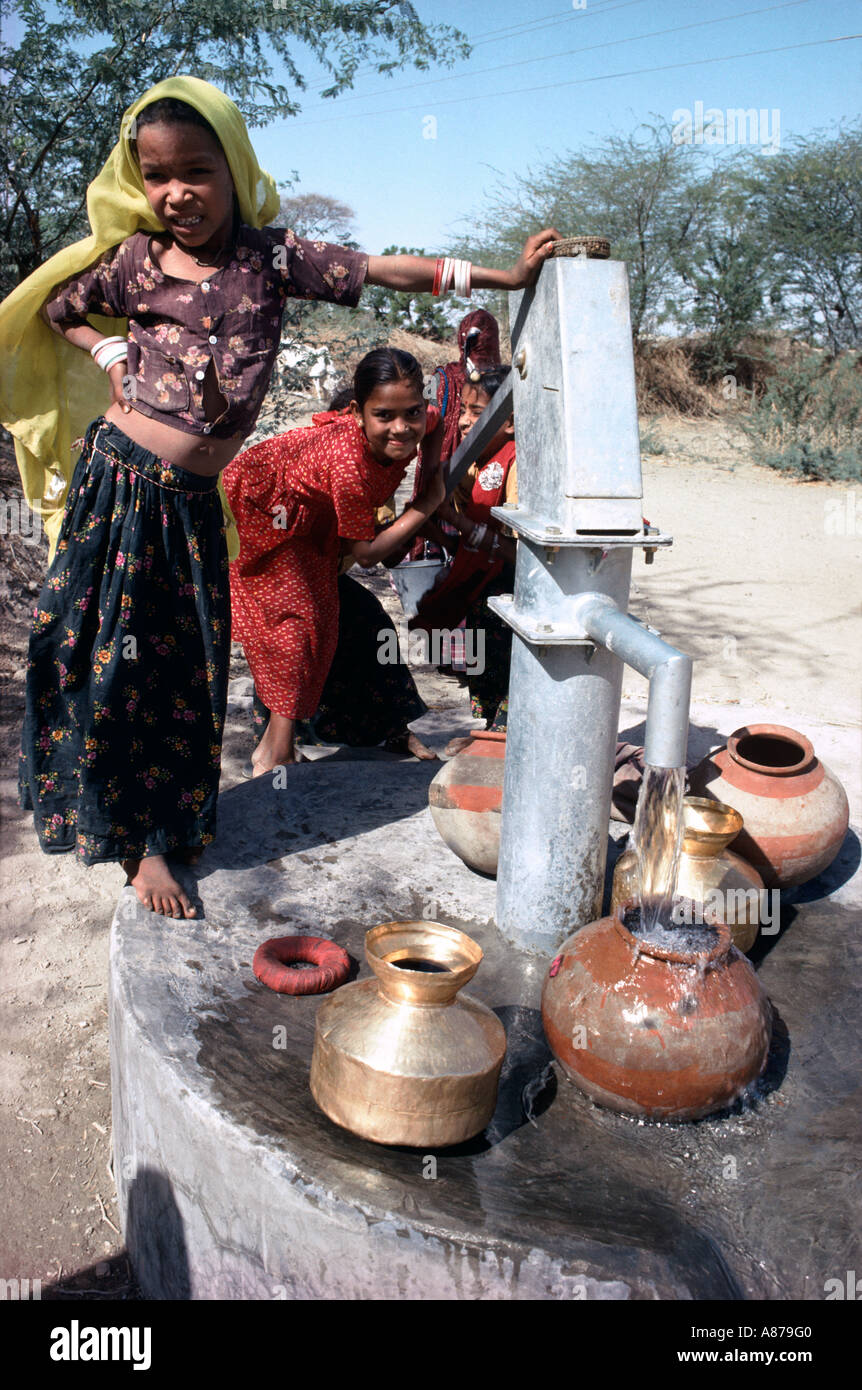 Le ragazze giovani pompano acqua al pozzo del villaggio. Rajasthan, India Foto Stock