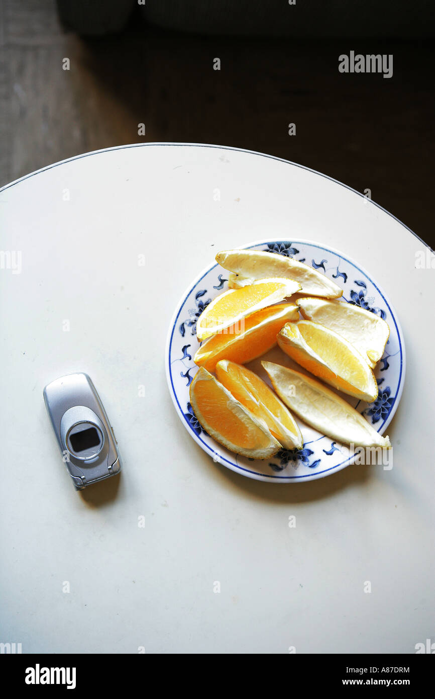 Fette di arancia e il telefono cellulare sul tavolo Foto Stock