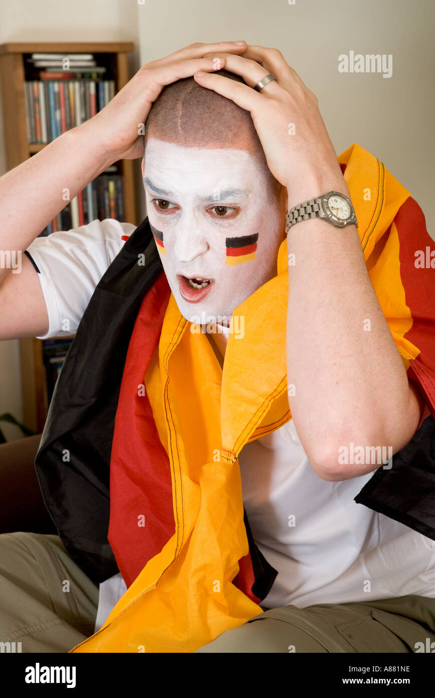 Modello rilasciato. Il tedesco tifoso seduto sul divano guardando la TV cercando sconvolto come team ha appena perso. Foto Stock