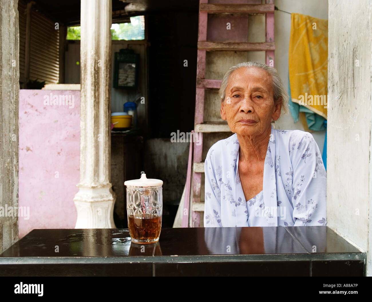 Donna anziana con un bicchiere di tè in delle baraccopoli di Surabaya, Java,Indonesia Foto Stock