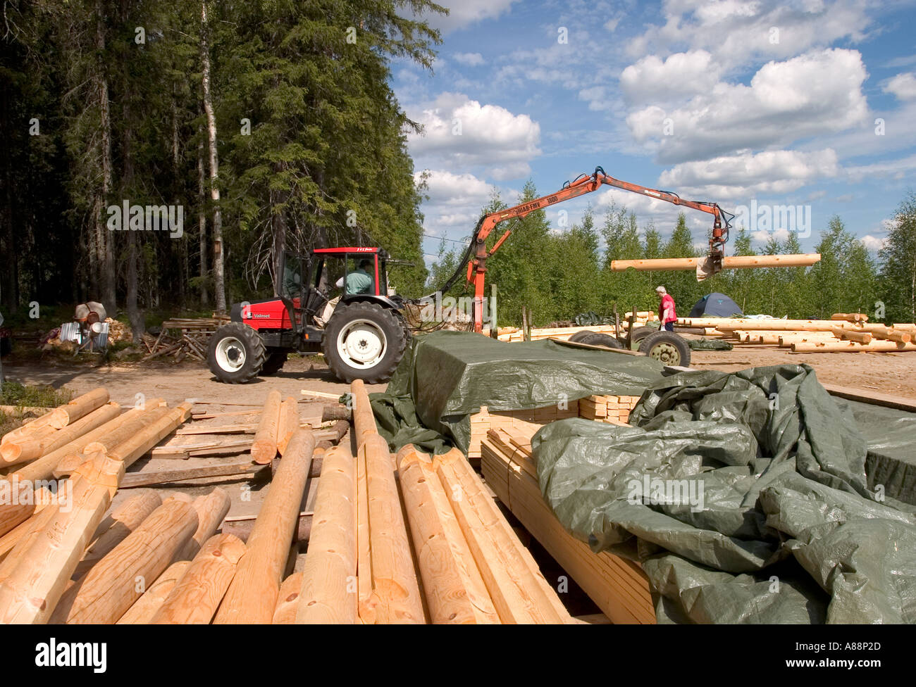 Materiali da costruzione per log cabin e un trattore a loro carico , Finlandia Foto Stock