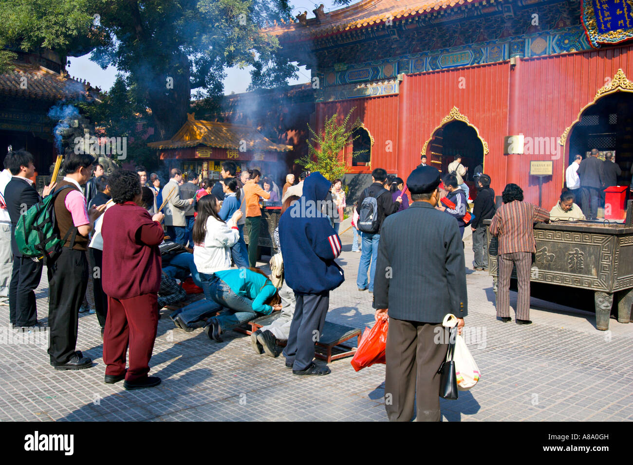 Cina Pechino buddisti cinesi bruciare incenso e si inginocchiano a pregare al di fuori del Palazzo della pace e armonia Yonghegong Tempio Lama Foto Stock
