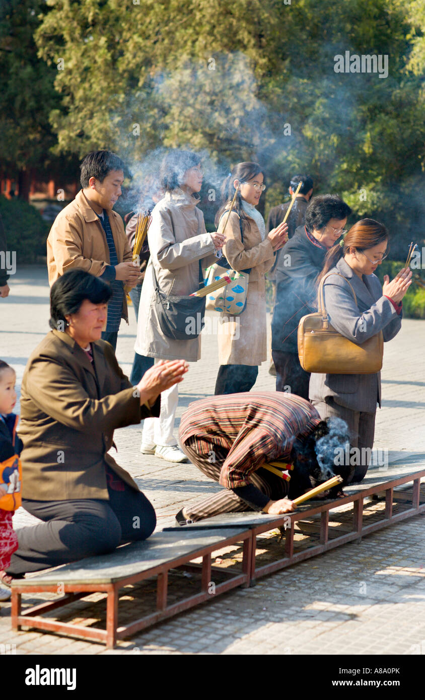 Cina Pechino buddisti cinesi bruciare incenso e si inginocchiano a pregare al di fuori del Palazzo della pace e armonia Yonghegong Tempio Lama Foto Stock