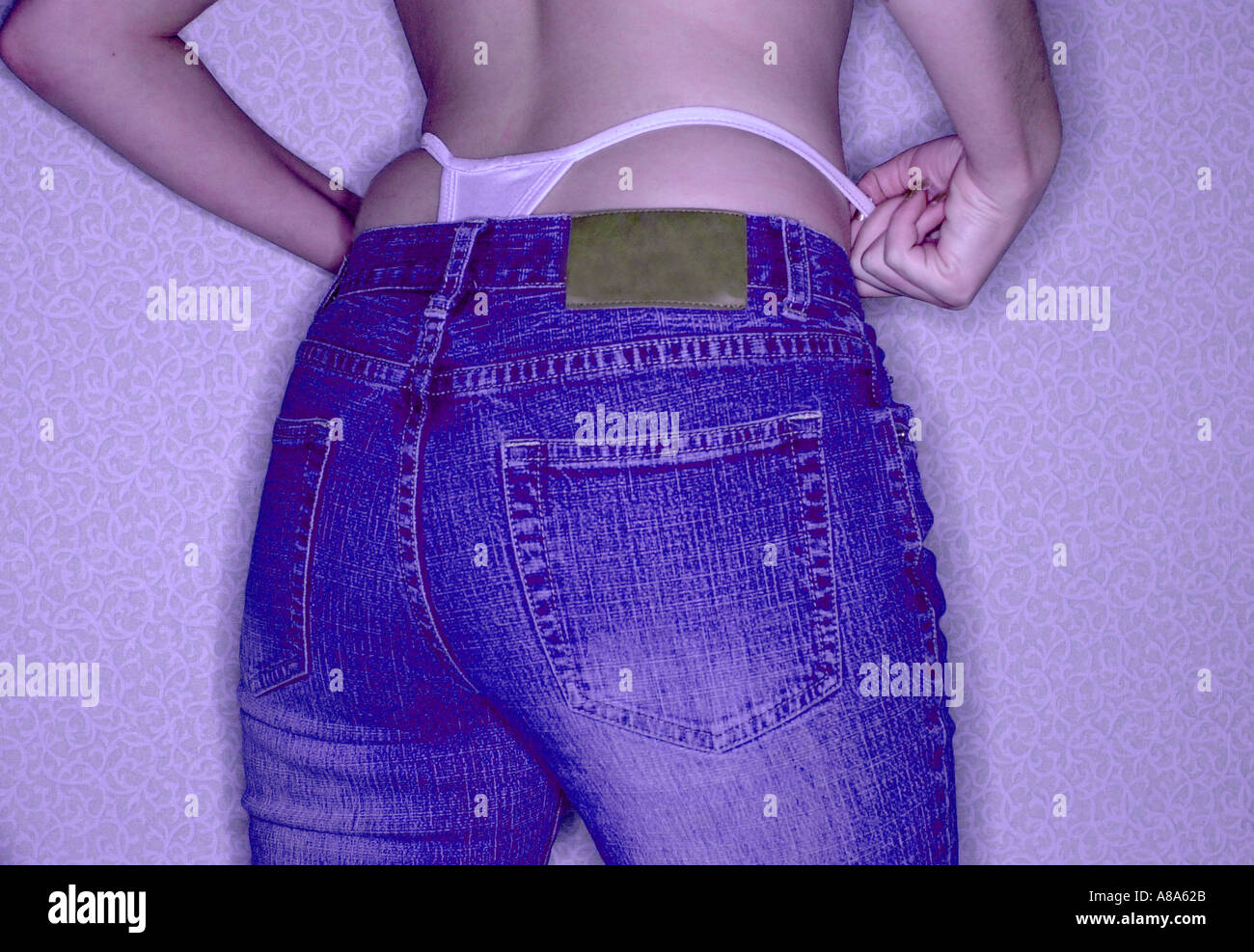 Donna in jeans con mutandine tanga che mostra i pantaloni di cui sopra Foto Stock