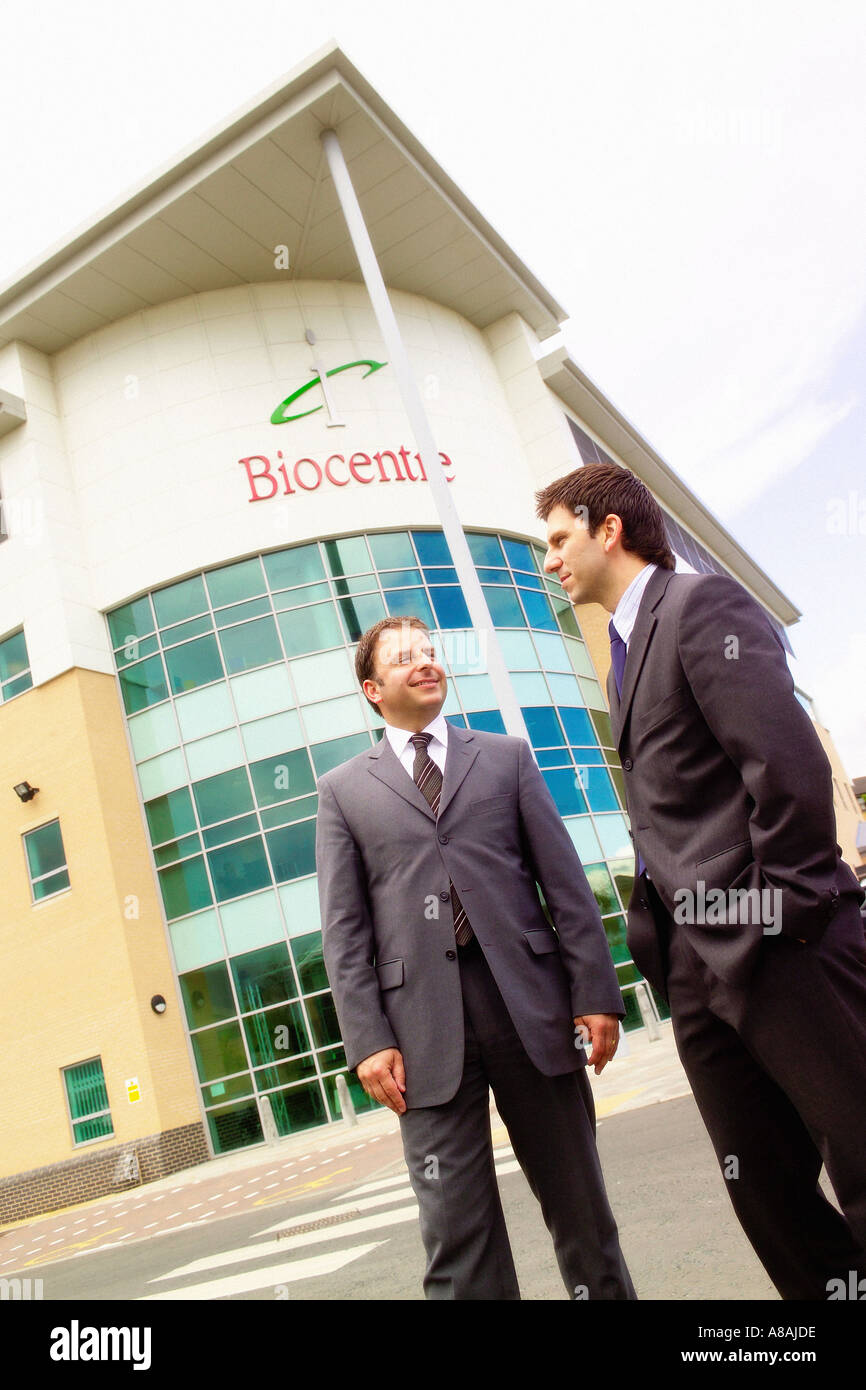 Foto angolata di 2 uomini che indossano abiti in piedi fuori dalla facciata contemporanea dell'ufficio del Biocenter, York Science Park. Foto Stock