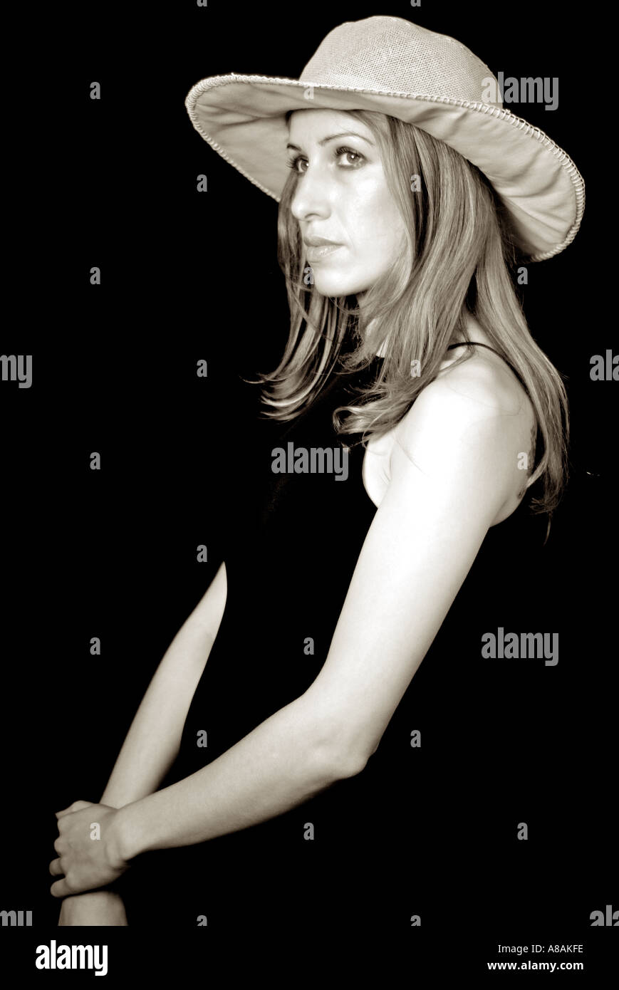 Giovane donna in abito nero e Hat contro uno sfondo nero Foto Stock