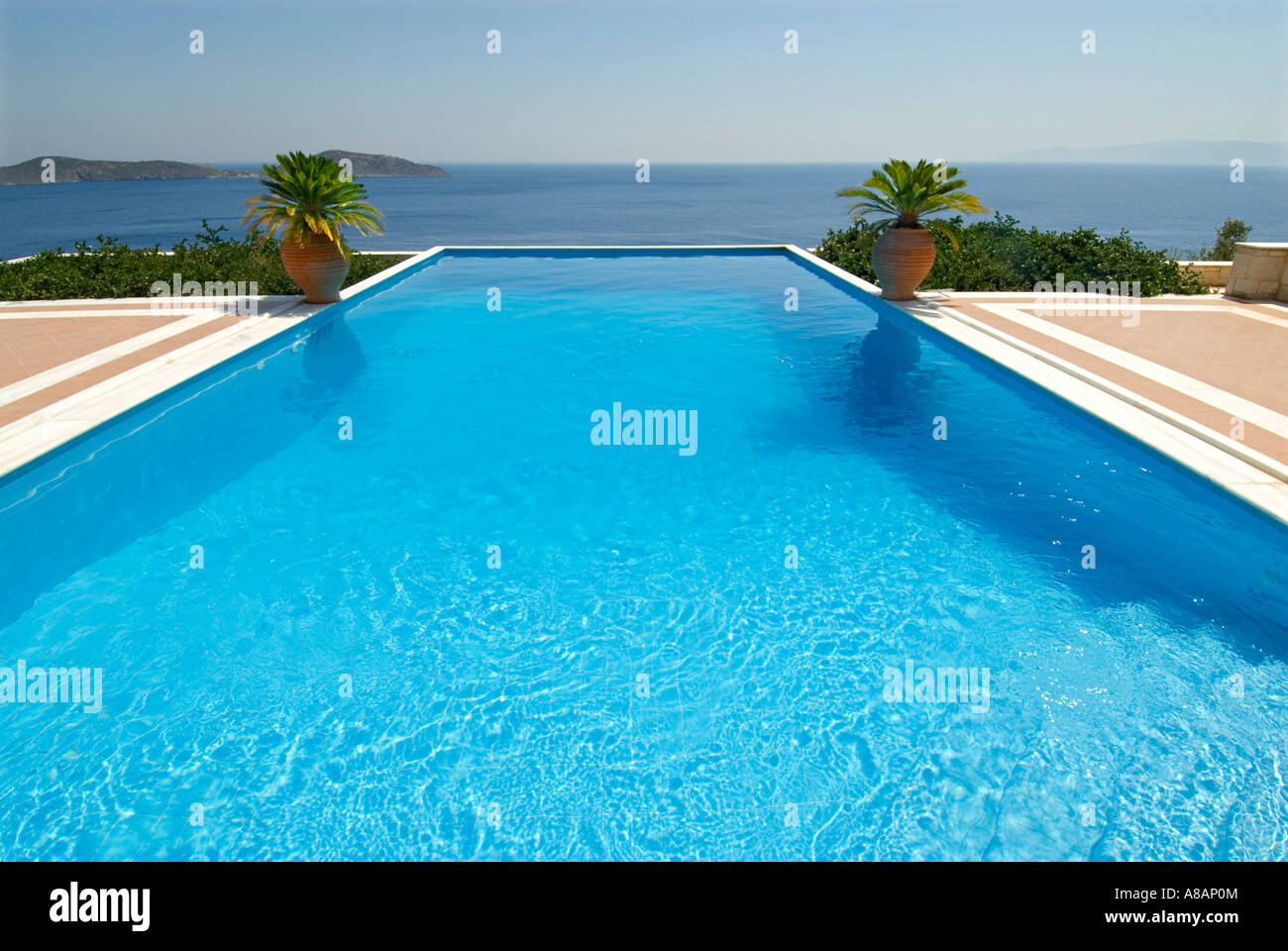 Esclusiva di lusso piscina infinity privata invitante un tuffo, affacciato sul Mar Egeo con palme e tipici grecian URN Foto Stock