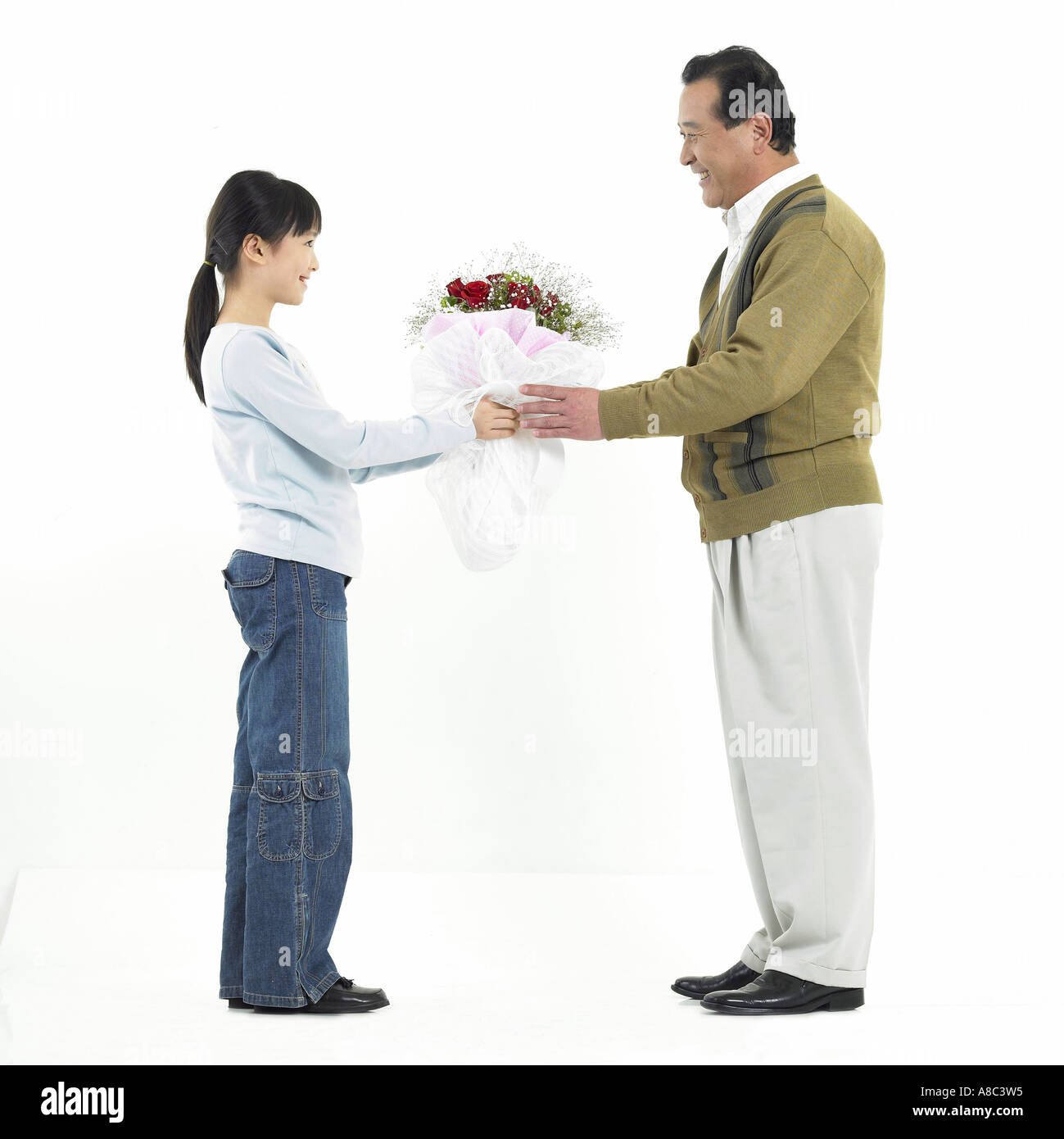 Famiglia una nipotina dando un bouquet di suo nonno Foto Stock