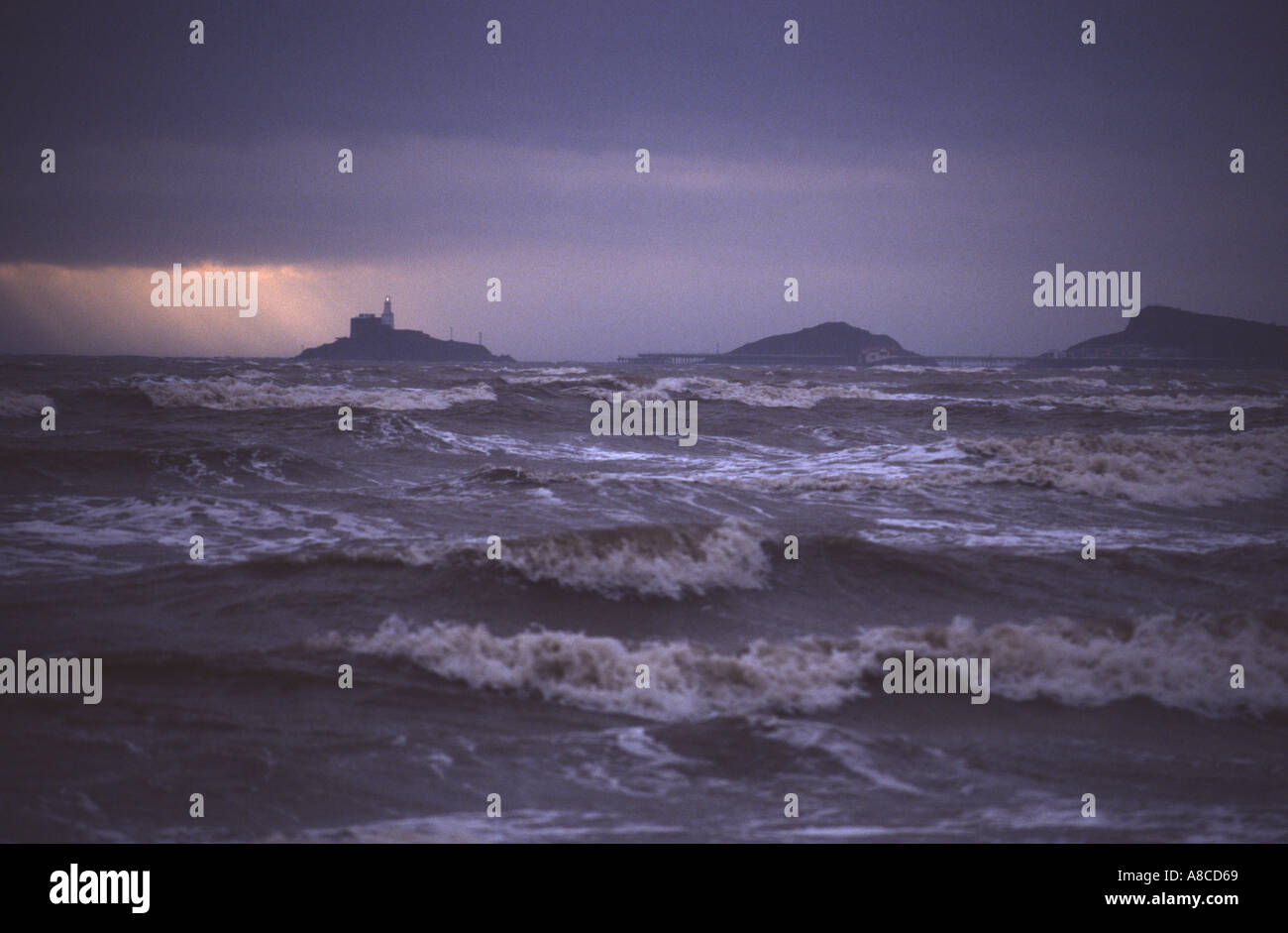 Tempesta con mare mosso a Swansea Bay, con MUMBLES testa e il faro in distanza, West Glamorgan, South wales, Regno Unito Foto Stock