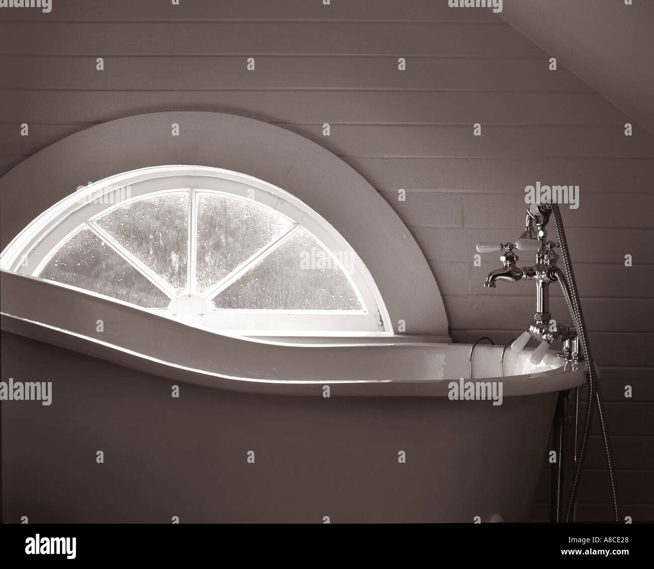 Antica vasca da bagno dalla finestra di luce dai toni seppia Foto Stock