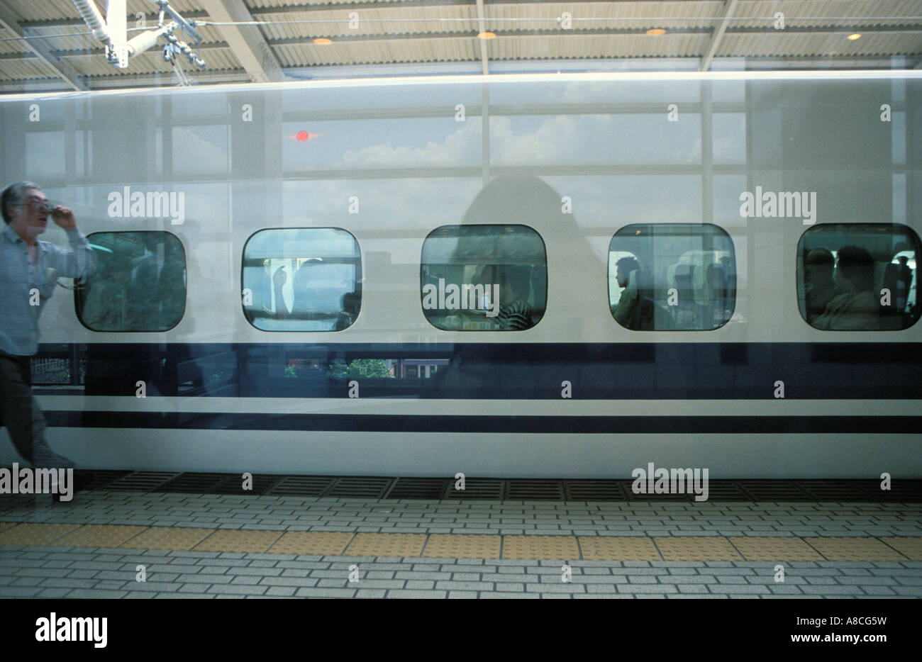 Uomo giapponese fretta lungo la piattaforma per catturare gli Shinkansen highspeed Bullet Train a Kyoto stazione ferroviaria, Giappone, Asia Foto Stock