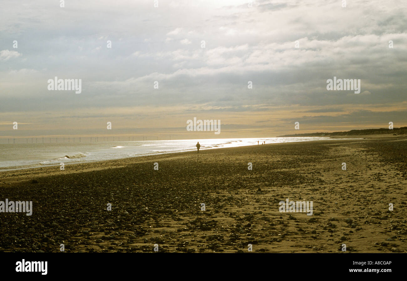 Figura solitaria,mattina presto,Winterton beach,per centrali eoliche in distanza,Costa North Norfolk,l'Inghilterra,UK Foto Stock