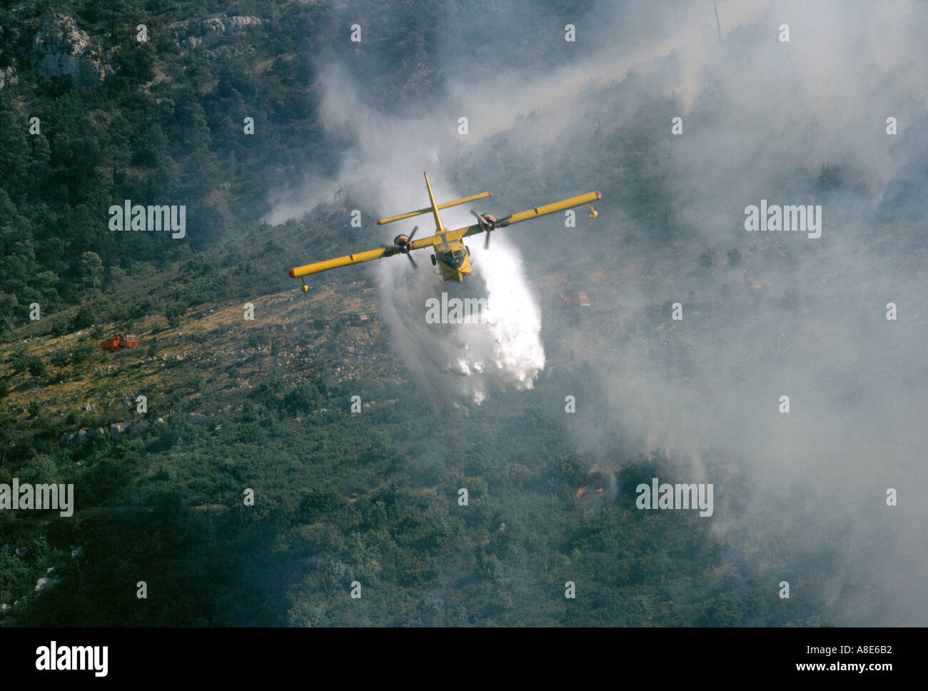 Vista aerea di un Canadair idrica antincendio aereo bombardiere spegnimento acqua su un wildfire, foresta incendio fumo, Provenza, Francia, Europa Foto Stock