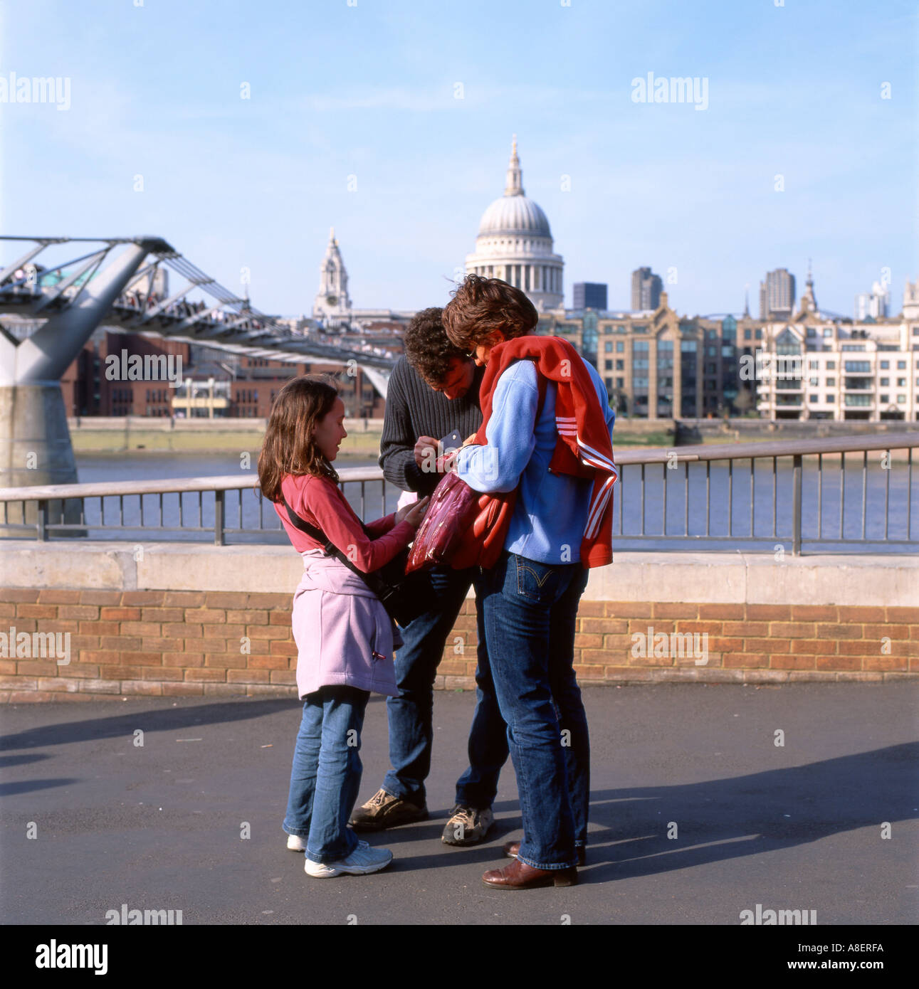 Una famiglia turisti visitatori madre padre bambino in una giornata fuori guardando una mappa dal Millennium Bridge, South Bank a Londra Inghilterra KATHY DEWITT Regno Unito Foto Stock