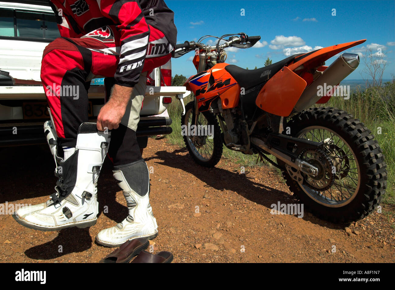 Un giovane uomo mette su bianco stivali da cavallo prima in sella alla sua  KTM Moto Foto stock - Alamy