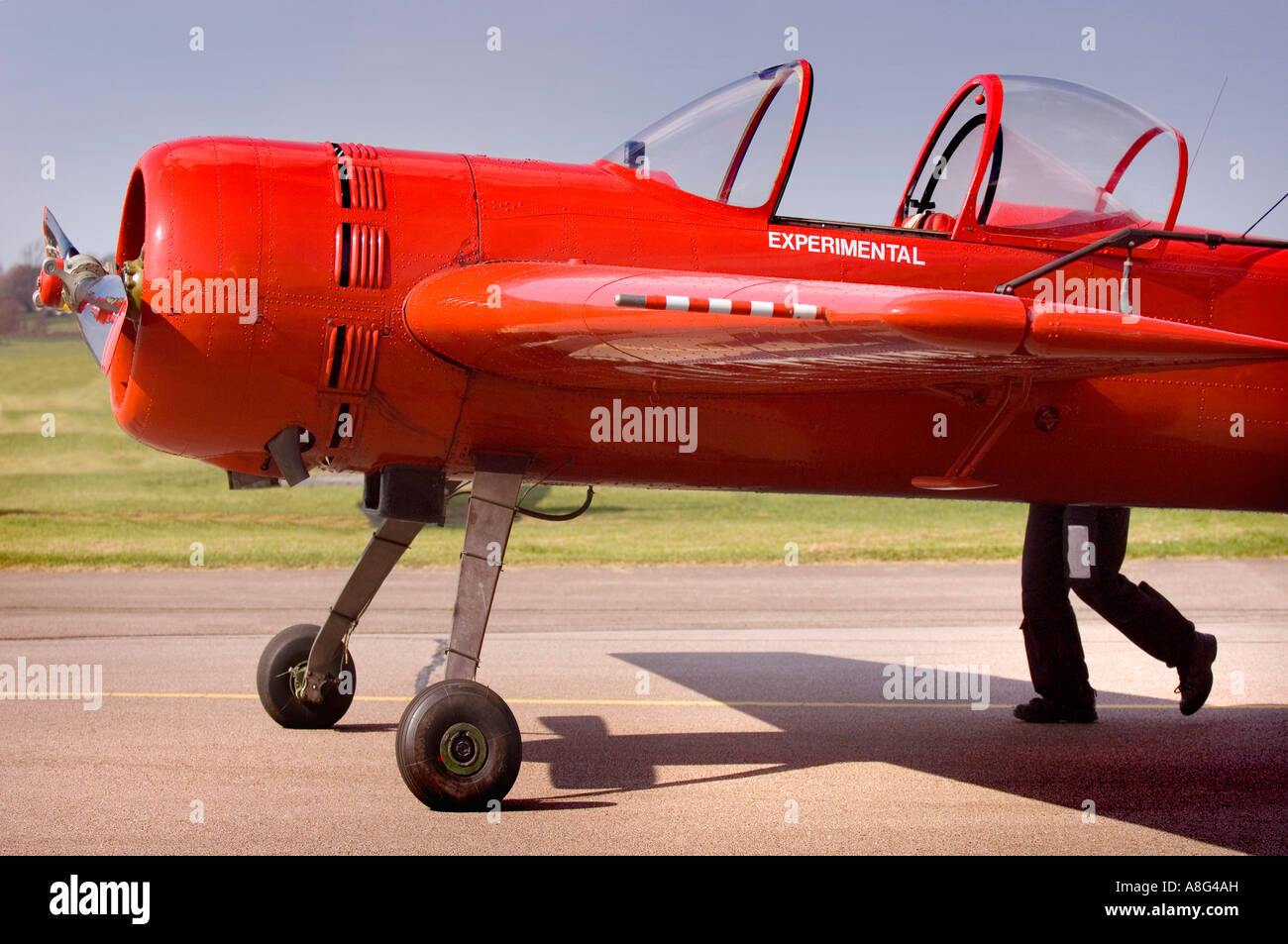 Wingnut: Un aereo rosso brillante sembra avere gambe, come un pilota spinge il suo aereo chiamato 'sperimentale' su una pista all'aeroporto di Shoreham, West Sussex, Regno Unito Foto Stock