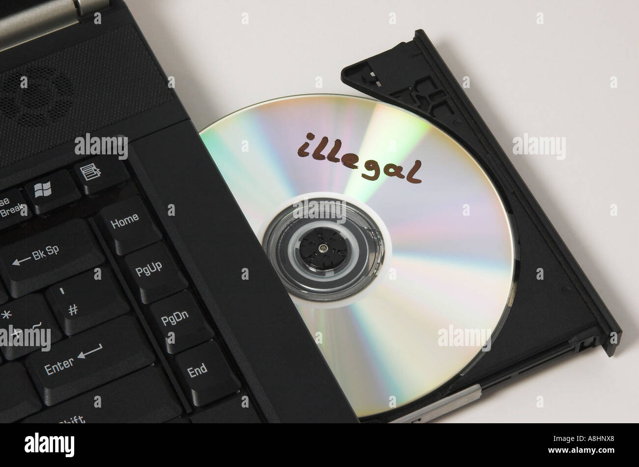 CD ROM con l'etichetta "illegale" giacente in unità CD di un computer notebook Foto Stock