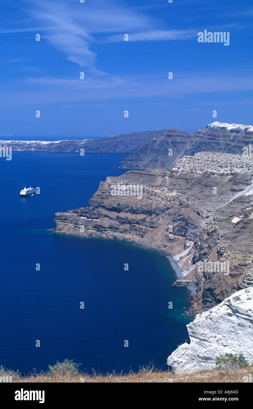 Grecia Santorini caldera drammatica vista della ripida scogliera i lati con il Mediterraneo e la piccola nave da crociera in distanza sopra Foto Stock