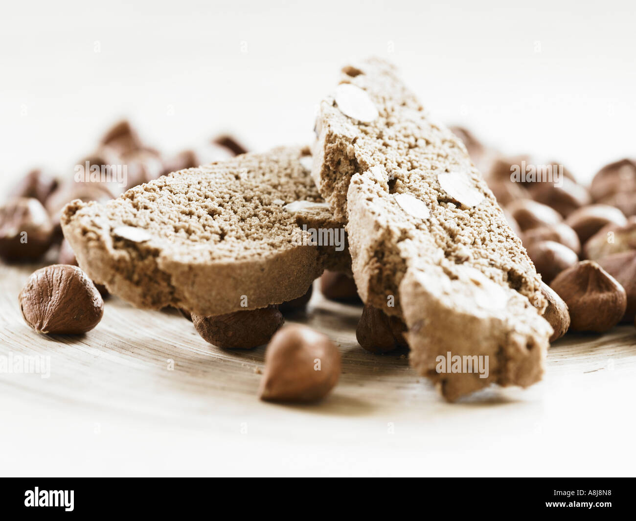 Biscotti di nocciole biscotto in pila sul complesso di nocciole sgusciate close up imbiancati fuori Foto Stock