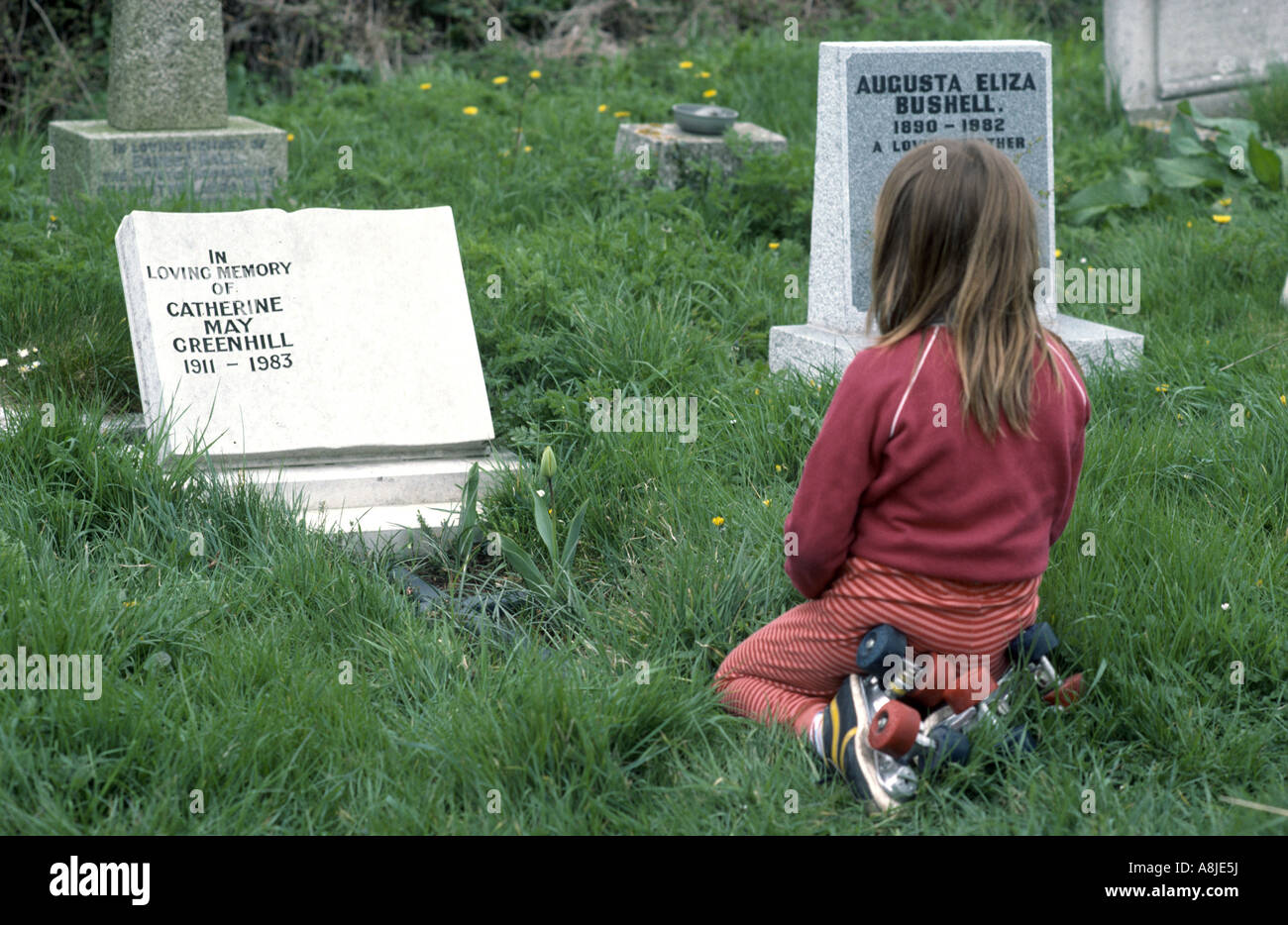Giovane ragazza si siede di fronte a nonna tomba Foto Stock