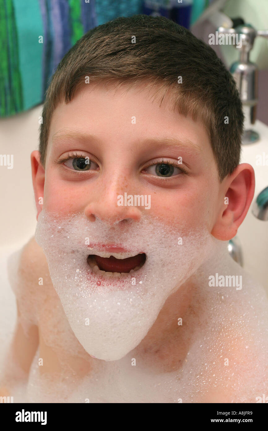 Un bambino di nove anni godendo un bagno di bolle. Foto Stock