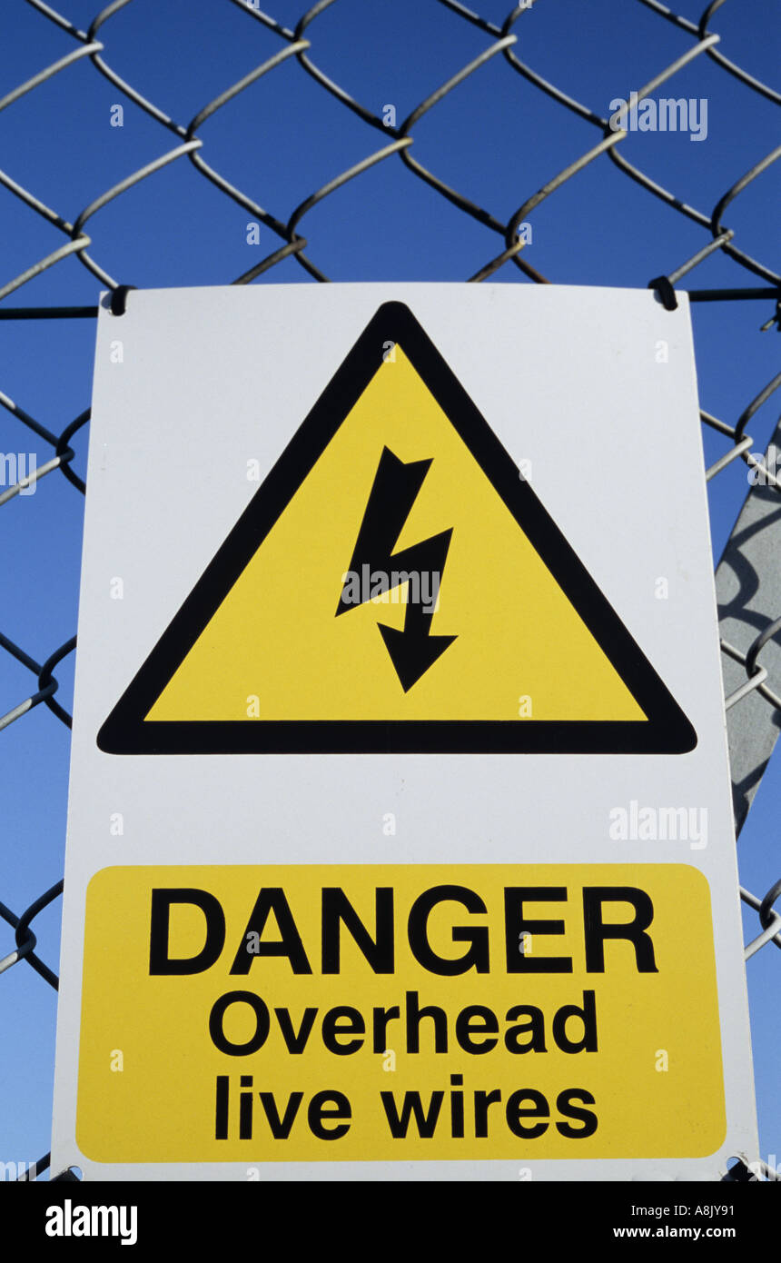Avviso con scosse elettriche icona indicante Pericolo cavi aerei sotto tensione sul collegamento recinto contro un cielo blu Foto Stock
