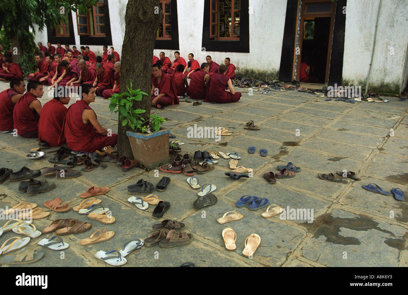 Decine di scarpe giacciono in attesa come centinaia di monaci chant al Drepung Gomang Monastery in India. Foto Stock