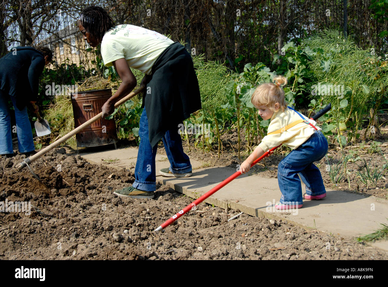 Donna e bambino zappando per preparare il suolo per coltivare ortaggi in London riparto in Peckham Foto Stock