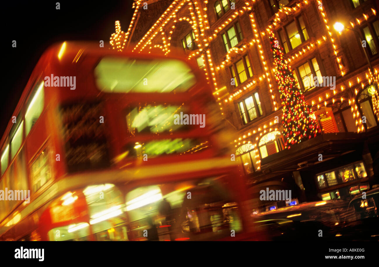 I grandi magazzini Harrods con albero di Natale e le luci con passaggio di sfocato red bus londinese di Knightsbridge London REGNO UNITO Foto Stock