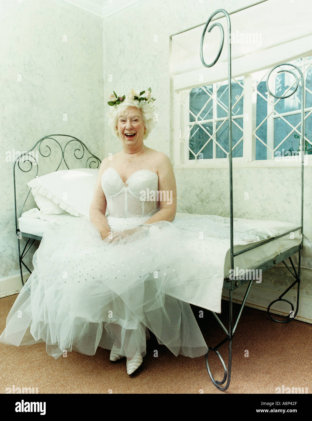 Donna anziana vestito in costume fata seduta sul bordo del letto di ridere  Foto stock - Alamy