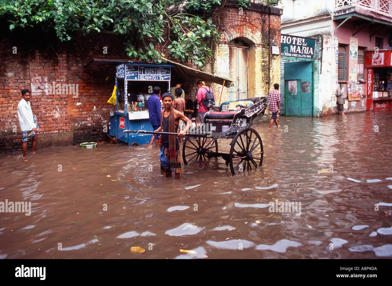 Un rickshaw driver trattare con le inondazioni causate dalle piogge monsoniche Foto Stock