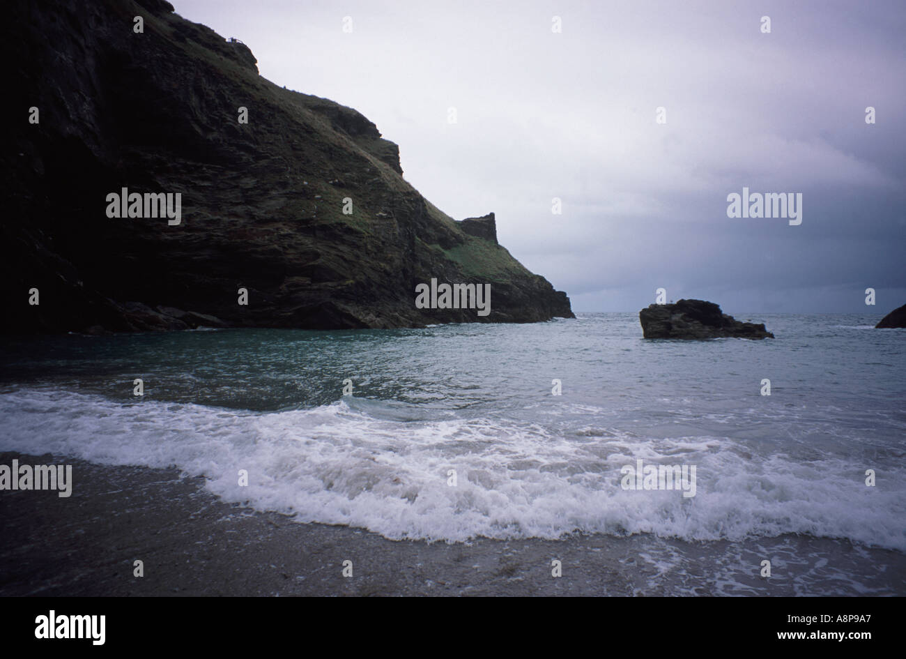 Spiaggia di sabbia e cala al di sotto di Tintagel Castle in alto sul rocciose scogliere della Cornovaglia Foto Stock