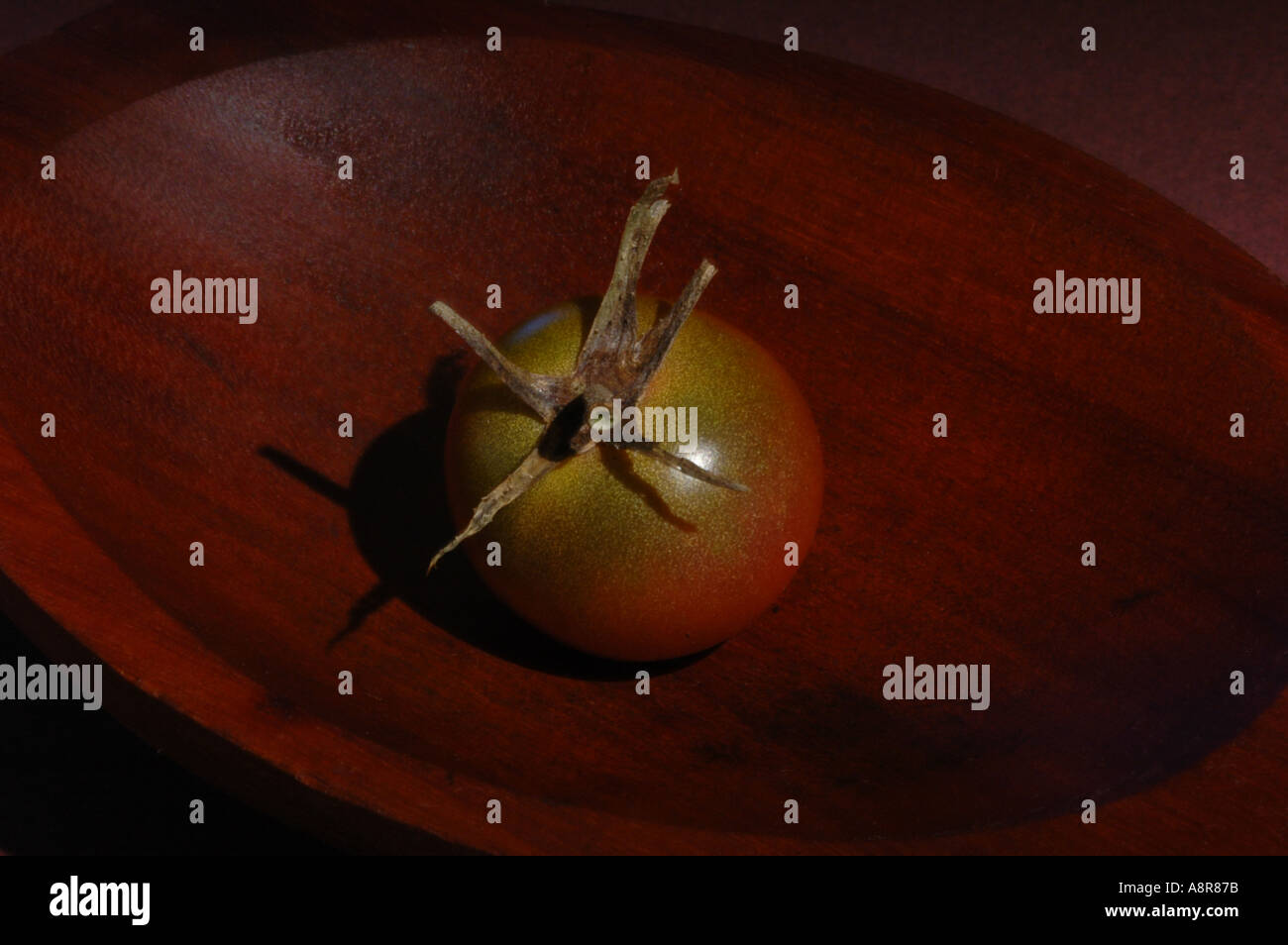 Un pomodoro ciliegino nella ciotola di legno Foto Stock