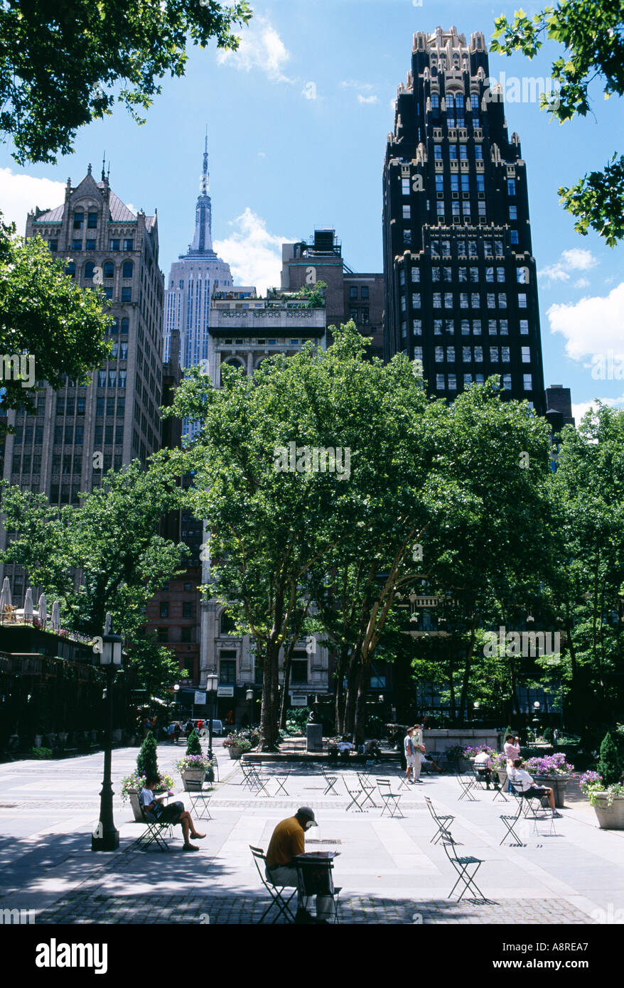 La gente seduta sulle panchine di fronte al Bryant Park hotel un grattacielo tra diverse in New York STATI UNITI D'AMERICA Foto Stock