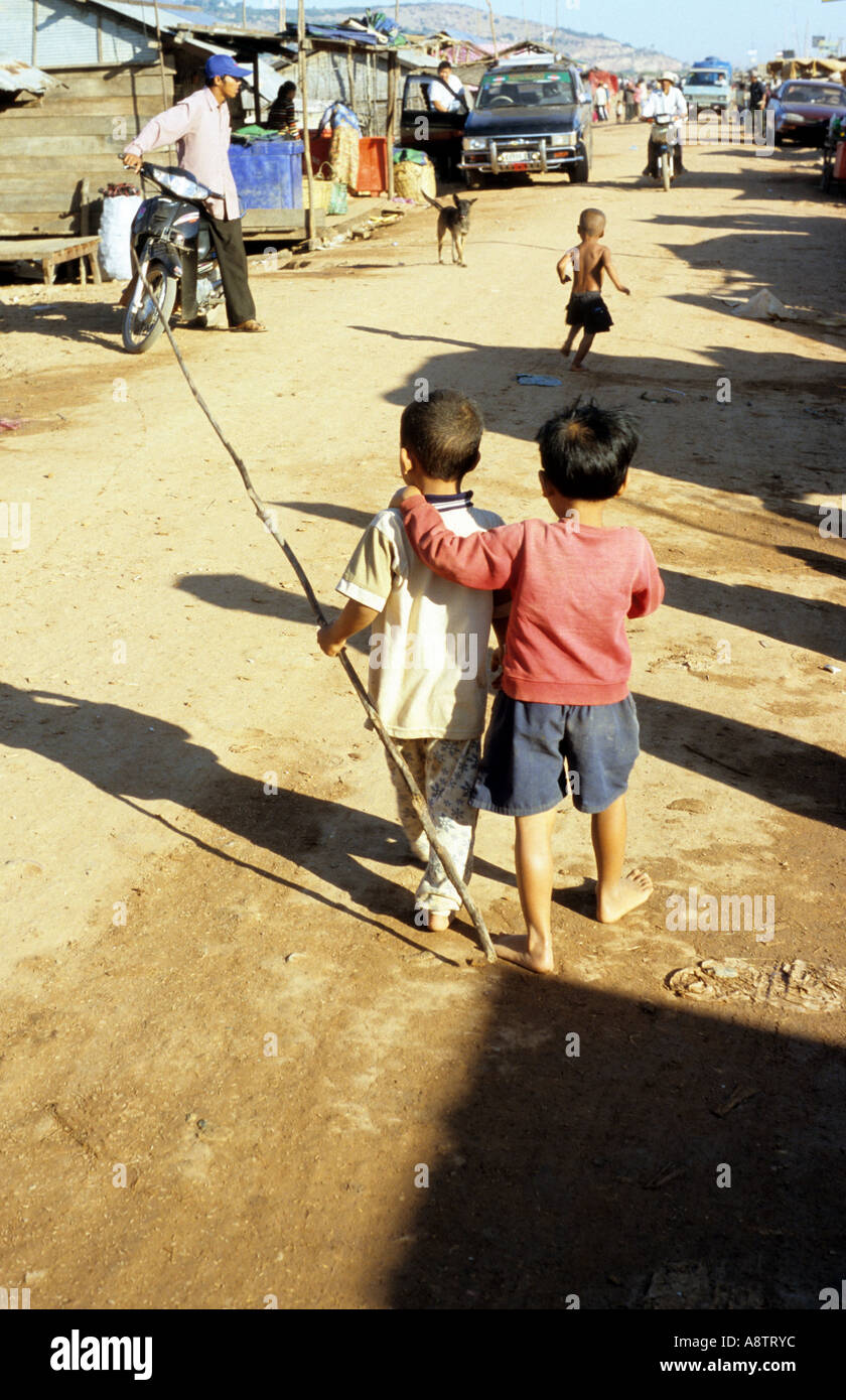 Due giovani ragazzi a camminare su una strada sterrata, Chong Kneas villaggio galleggiante, il Tonle Sap, Siem Reap, Cambogia Foto Stock